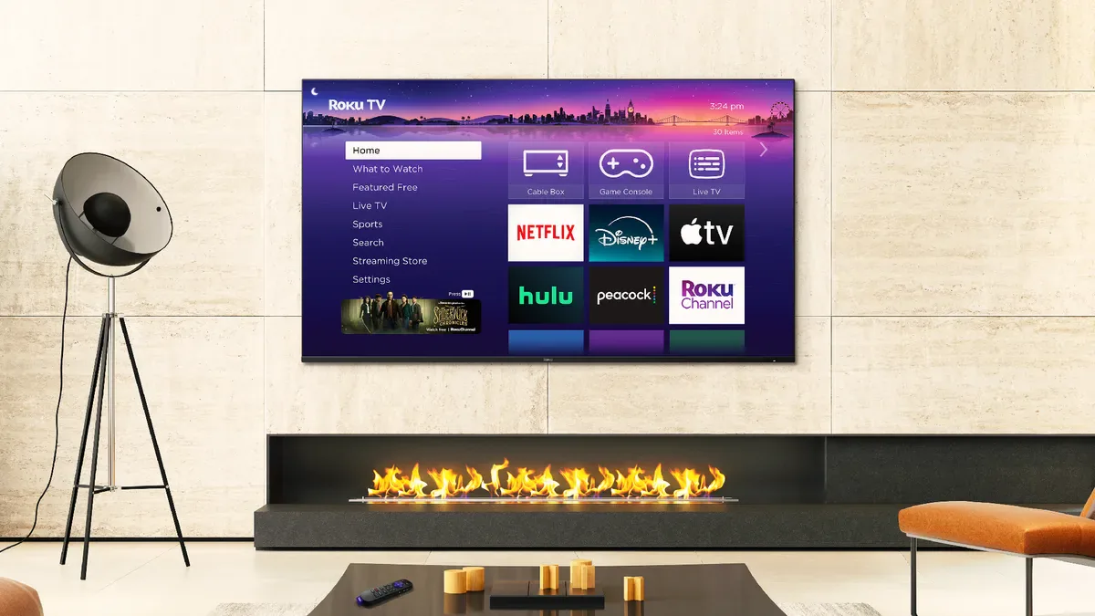 Wall-mounted Roku TV showing the streaming app home screen above a linear fireplace