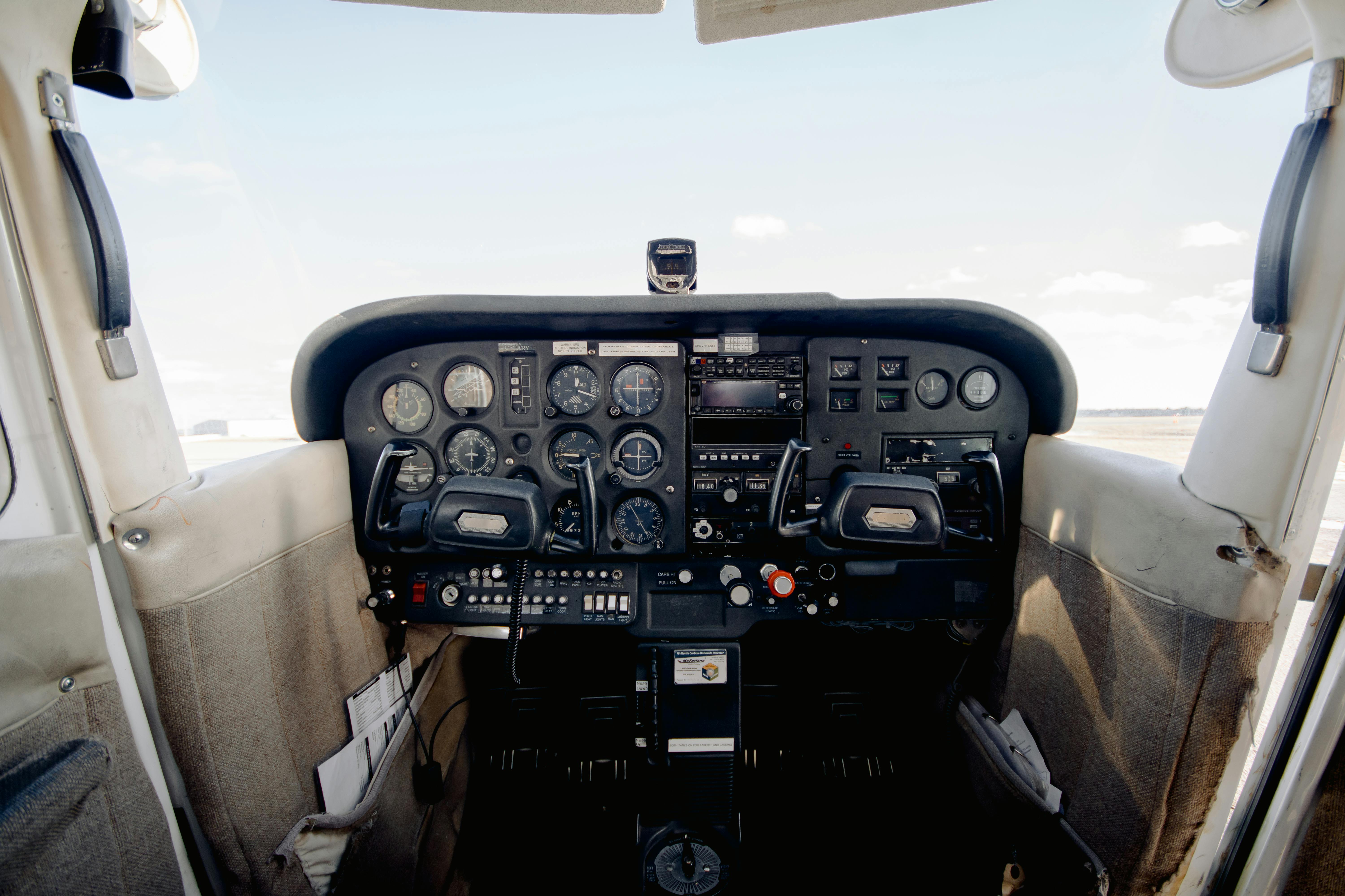 Cockpit of a small airplane showing flight instruments, control yokes, and radio panels.