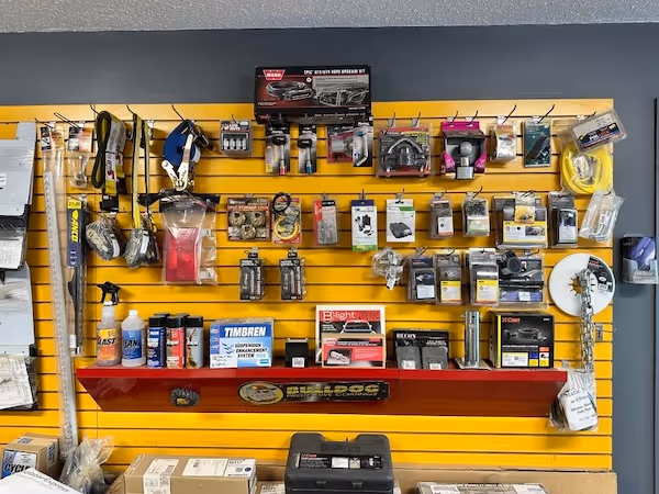 Store display with various automotive parts and accessories hanging on a yellow slatwall and placed on a red Bulldog-branded shelf.
