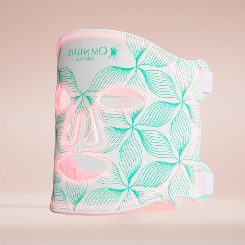 White LED face mask with green leaf patterns and cutouts for eyes, nose, and mouth.