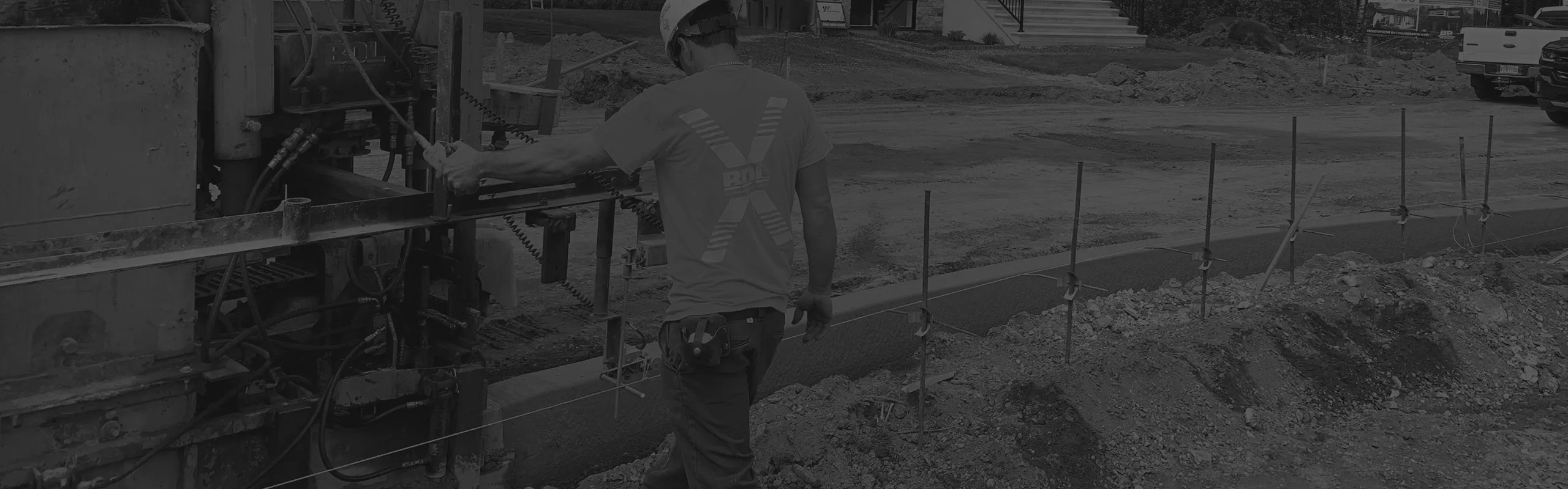 Travailleur portant un casque commandant une machine de construction pour couler un trottoir en béton.