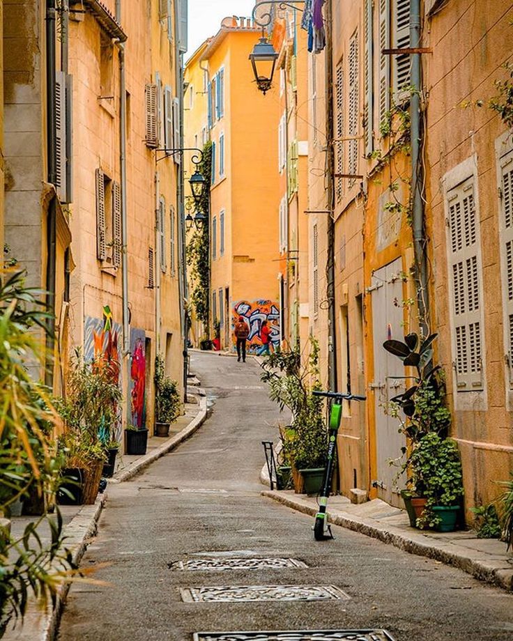 This may contain: an alley way with people walking down one side and graffiti on the other in between
