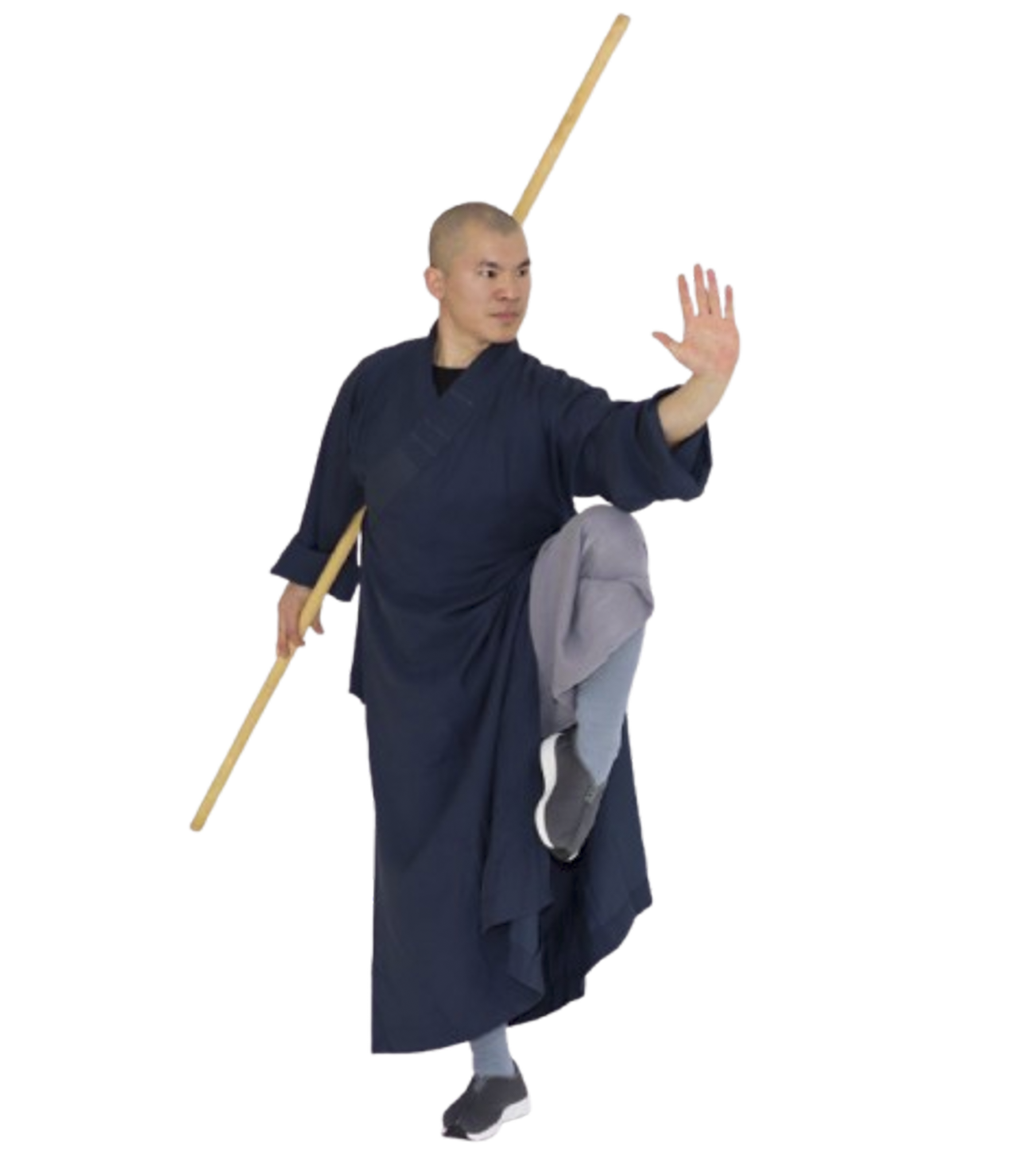 Martial artist in dark traditional clothing balancing on one leg while holding a wooden staff and extending one hand forward.