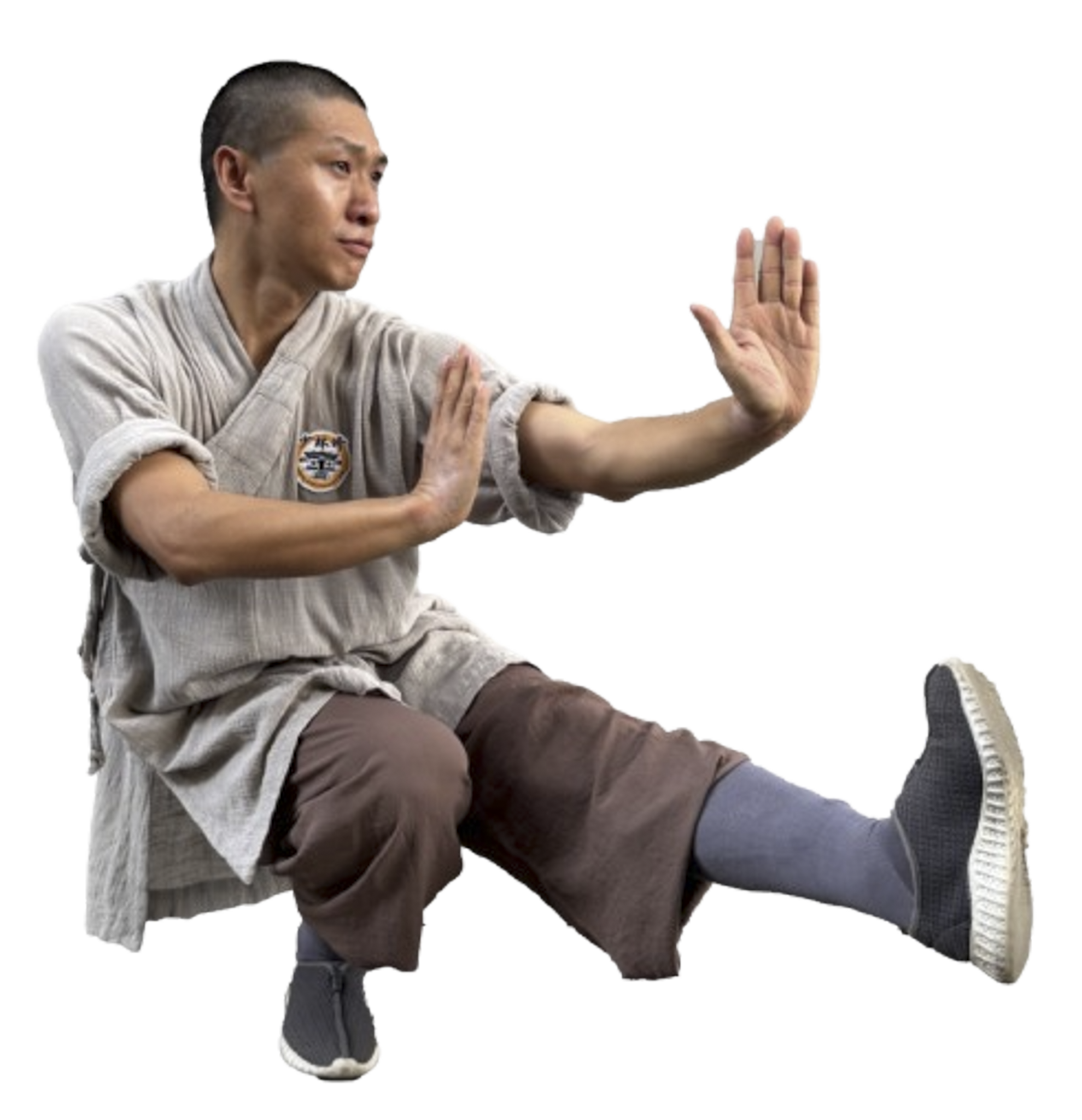 Man in traditional martial arts attire performing a balanced side kick with both hands raised in a defensive stance.