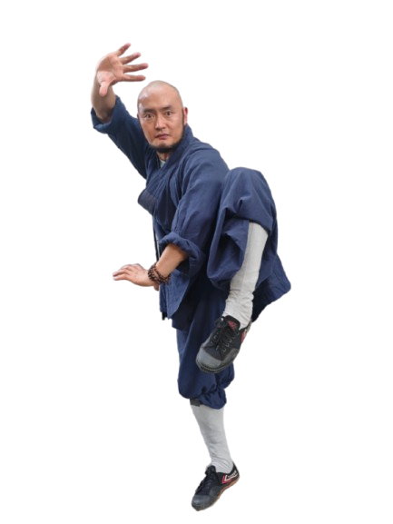 A man in traditional dark blue martial arts attire performing a high kick with one hand extended forward and the other near his waist.