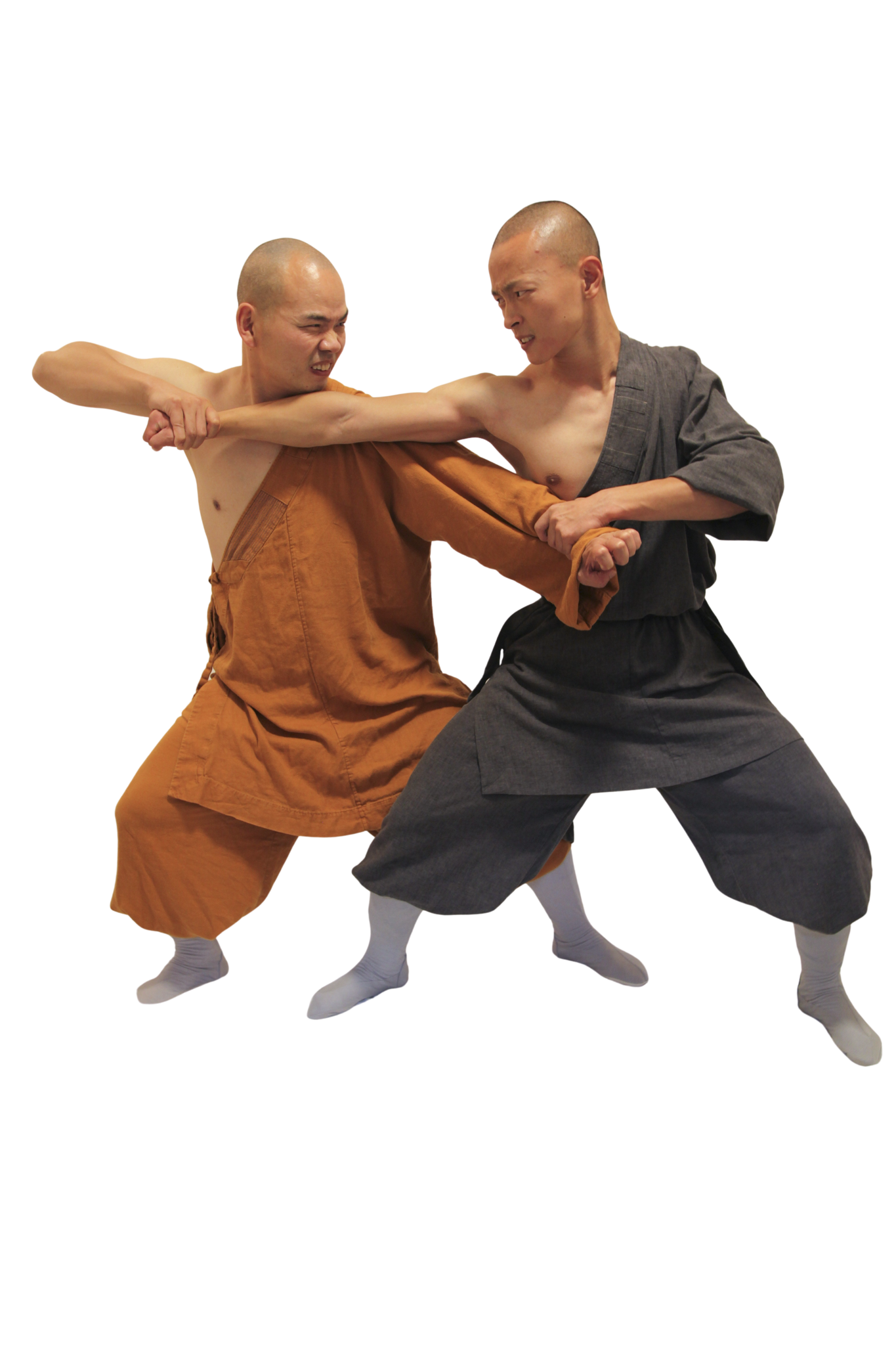 Two men practicing martial arts, one wearing brown traditional clothing and the other in dark gray, locked in a defensive arm grip.martial art london Shaolin Xiu