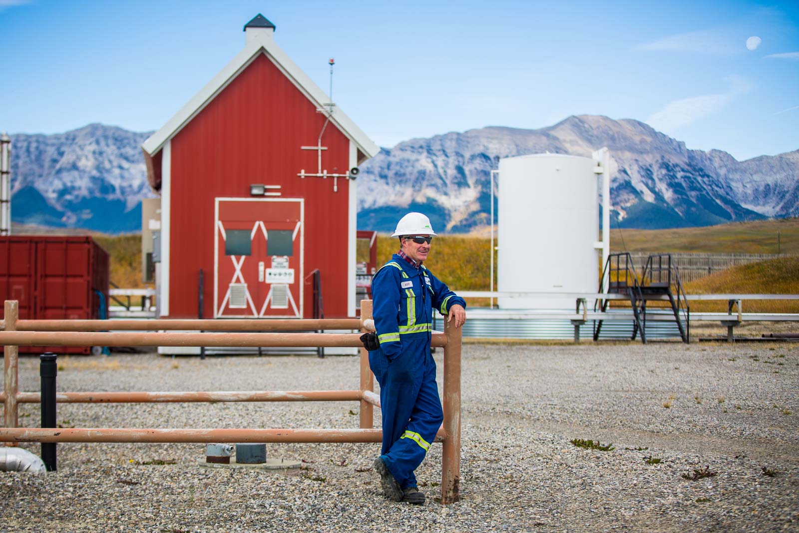 Operator in the field wearing PPE in front of an oil production location in Alberta.