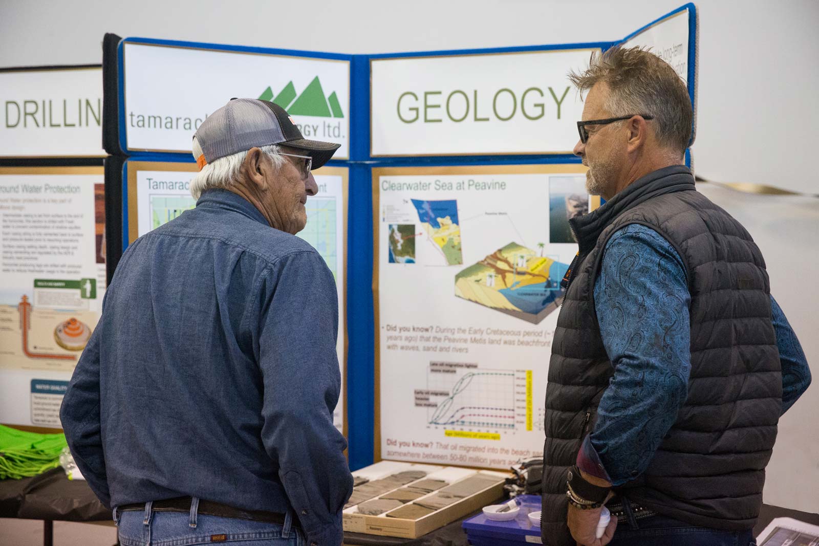 Two men talking in front of a geology display