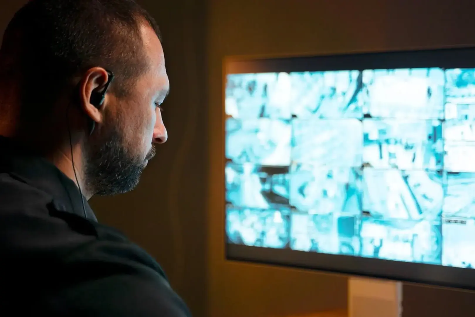 Security controller sitting and monitoring security and CCTV screens