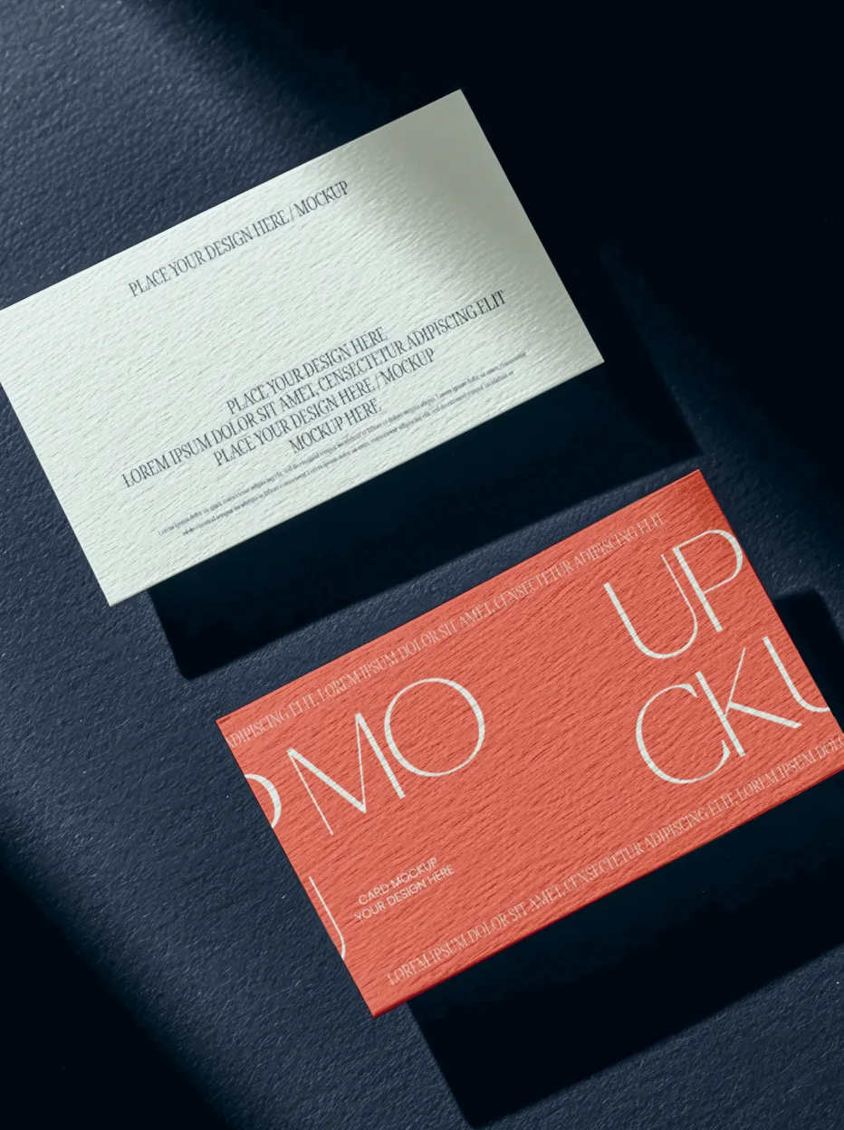 Two rectangular business card mockups on a textured dark surface, one light-colored with placeholder text and one red with large text reading 'MOCKUP'.
