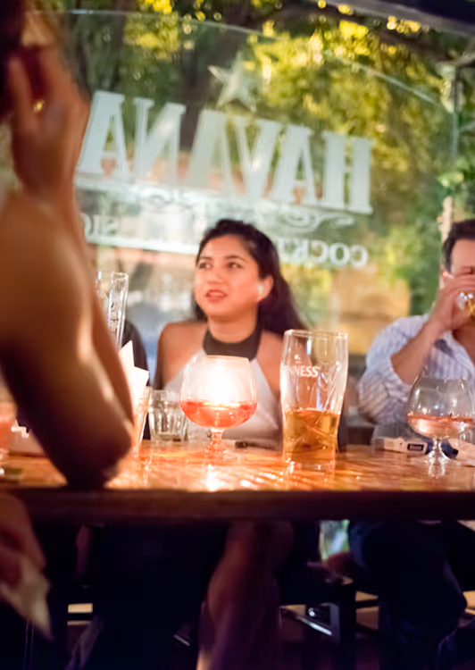 A woman in a white halter top sitting at a table with drinks in Havana.