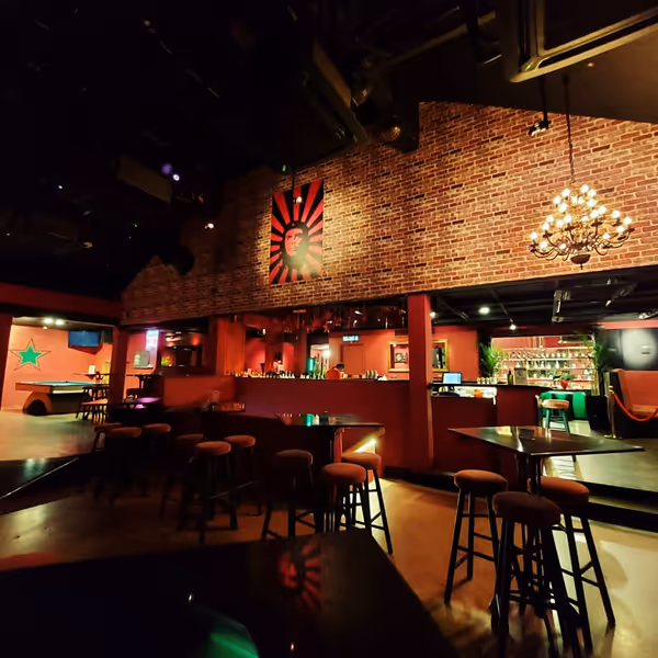 Havana interior with brick walls, round stools, a chandelier, and a red and black poster of a face on the wall.
