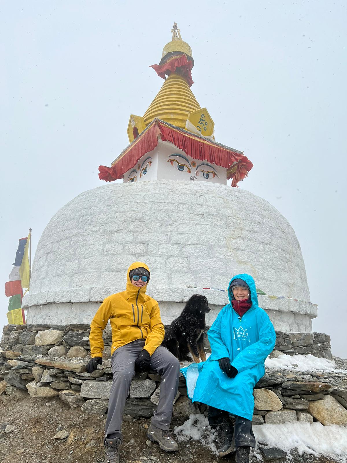 Kevin. Nepal EBC trek, trekkers sitting with dog by stupa in mist