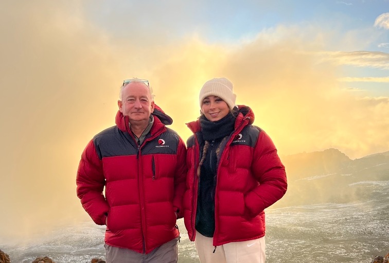 Alicia Garret. Young woman and older man at Uhuru Peak on Kilimanjaro, different ages climbers in Follow Alice jackets