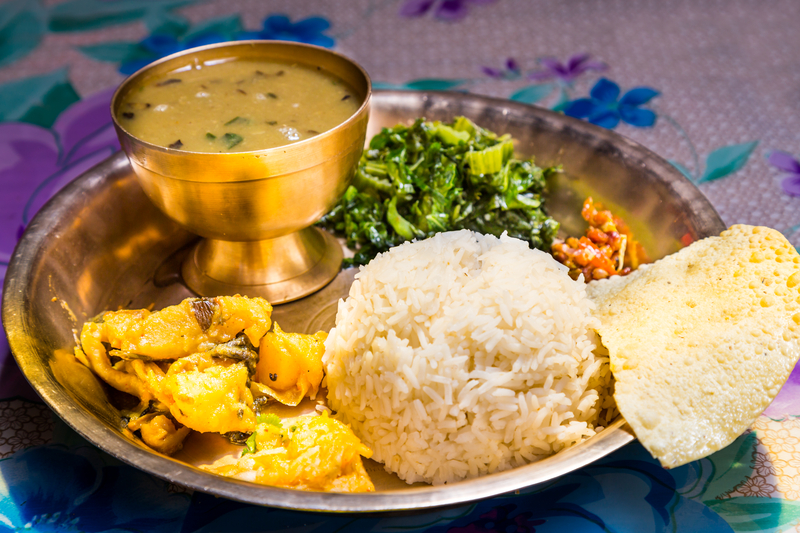 Ours. Nepali dal bhat with poppadam served in metal plate and sitting on a floral napkin