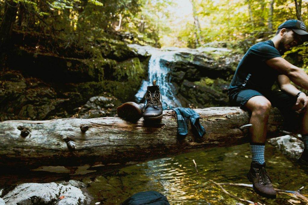 Man sitting on log over stream