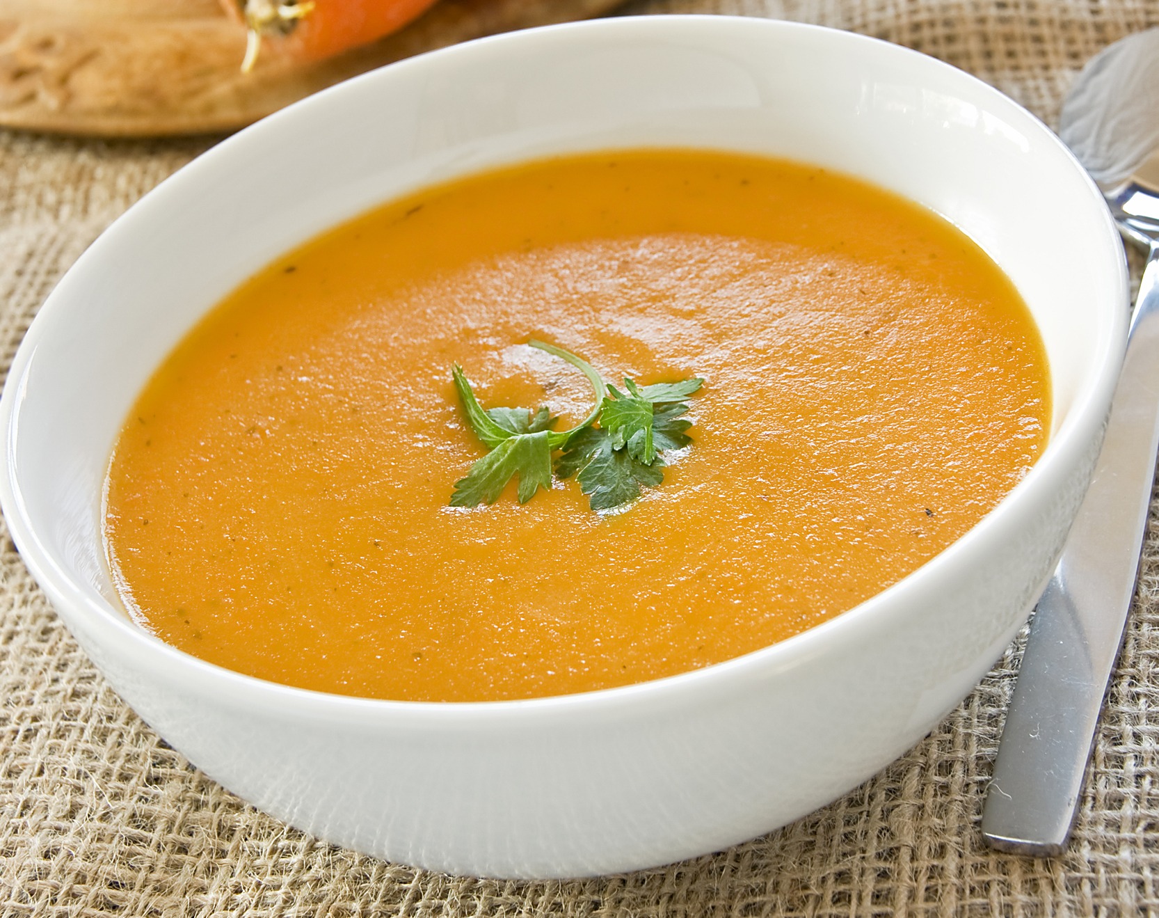 Ours. Carrot and coriander soup in a white bowl