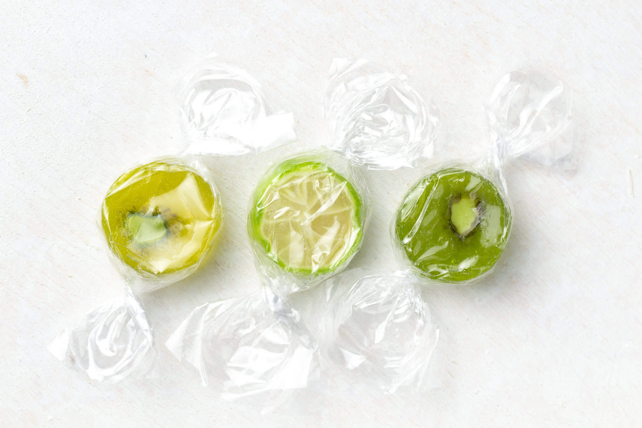 Ous. Green, individually wrapped sweets against white background