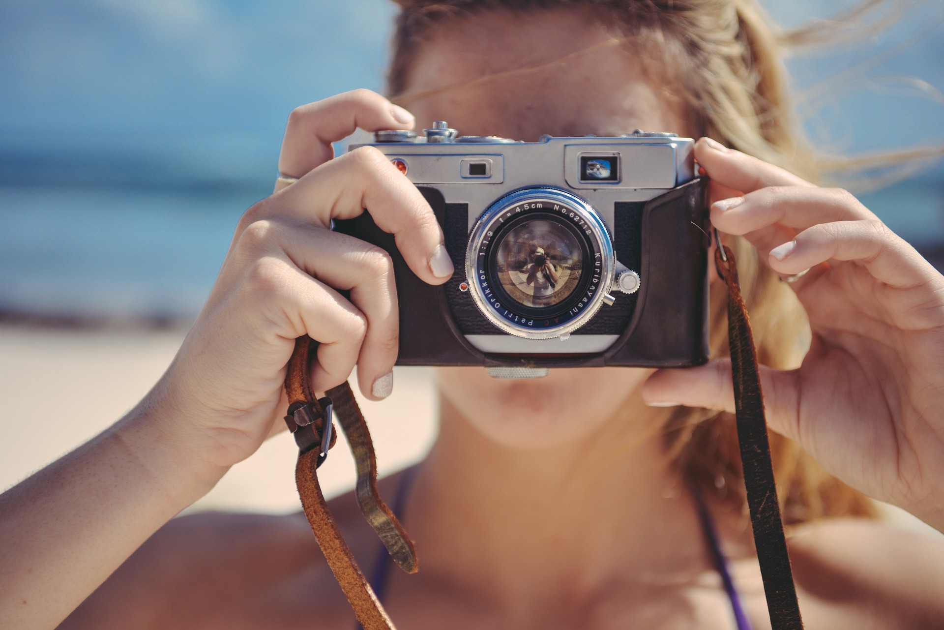Blonde girl looking into camera holding up a camera