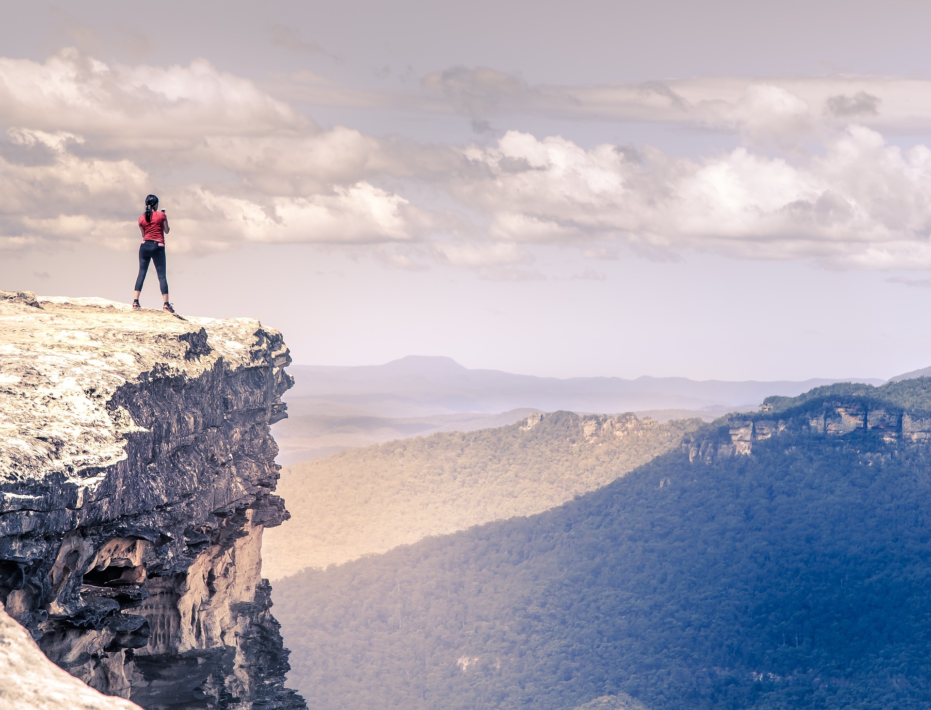 Woman on cliff looking at mountains