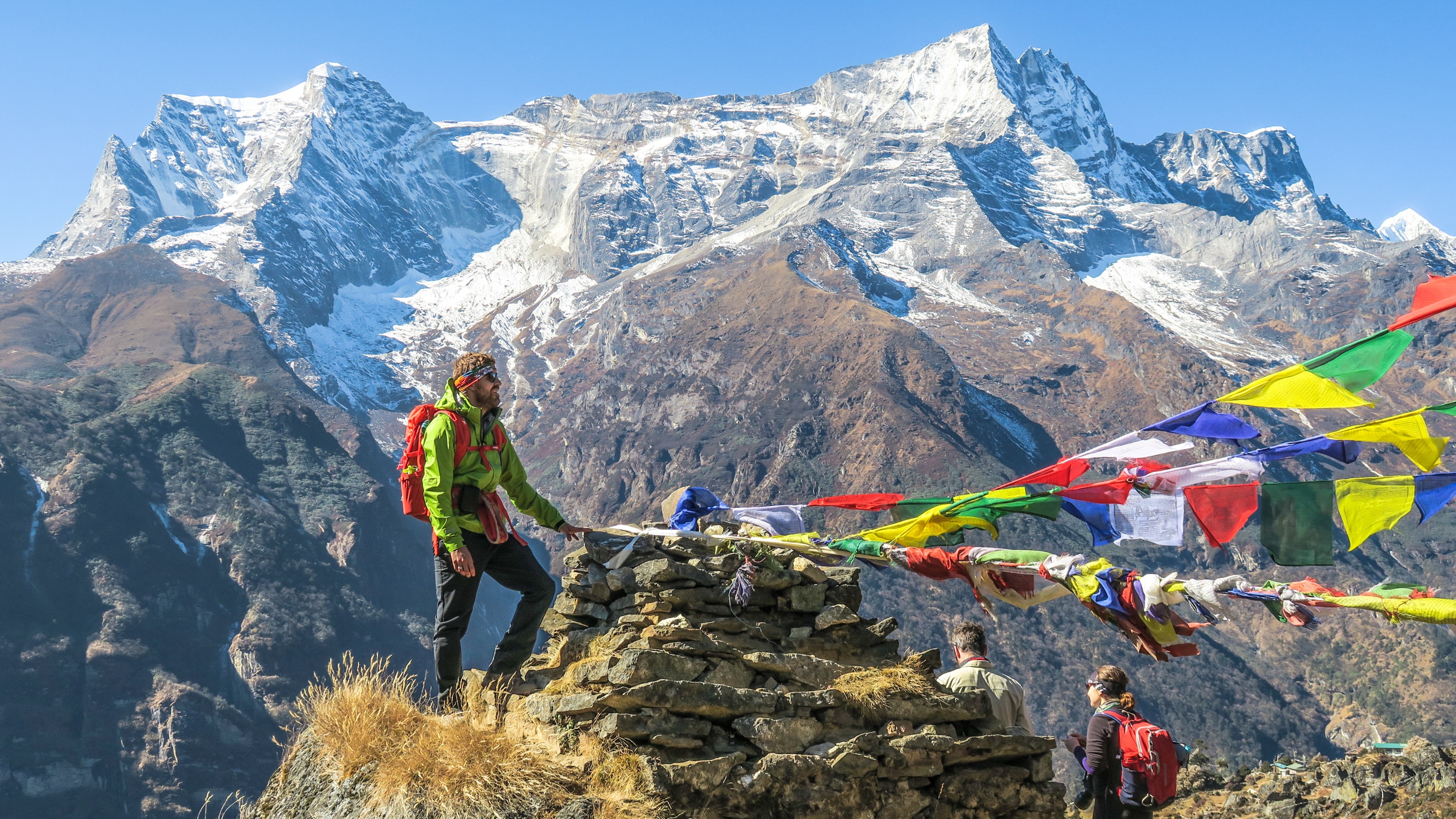 Trekkers standing by prayer flags near Namche Bazaar