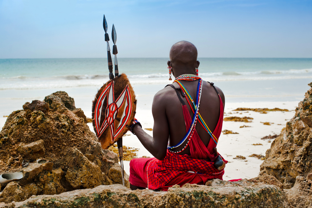 Ours, Masai warrior sitting on rock on beach in Kenya
