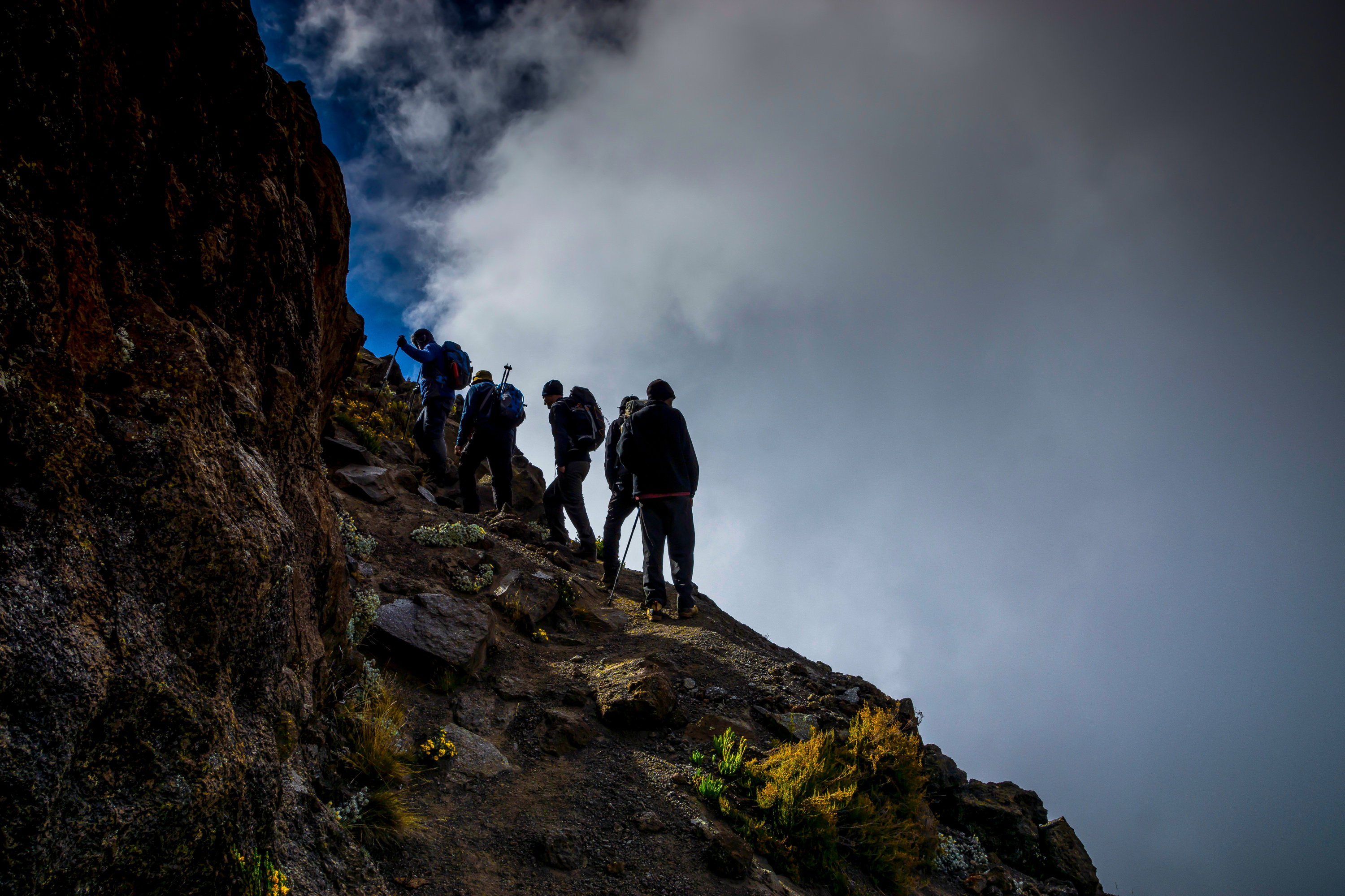 Trekkers on edge of Barranco Wall with clouds on right, Kilimanjaro