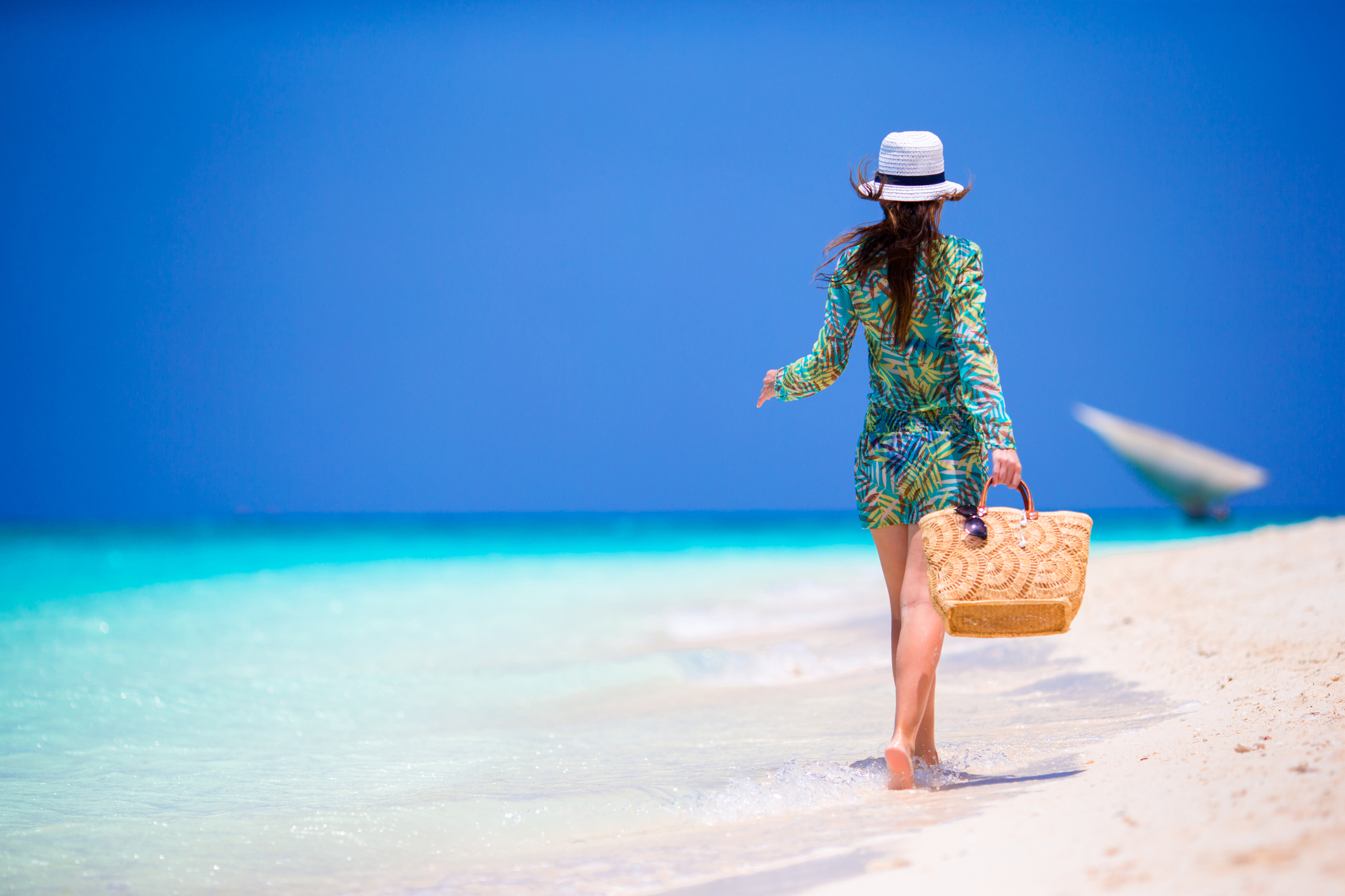 Woman walking barefoot along shoreline of beach in Zanzibar