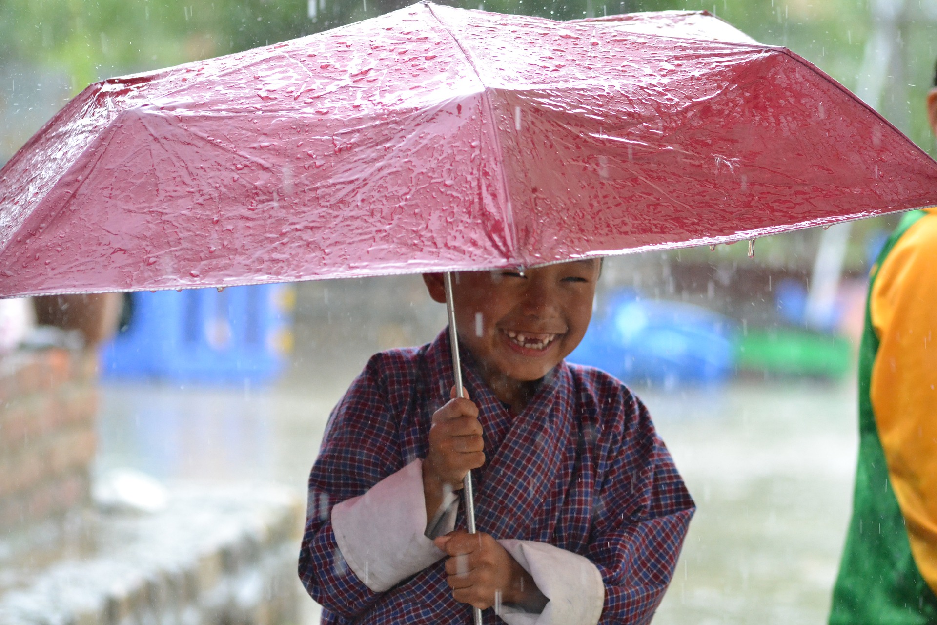 Rain and smiling boy with red umbrella, Bhutan
