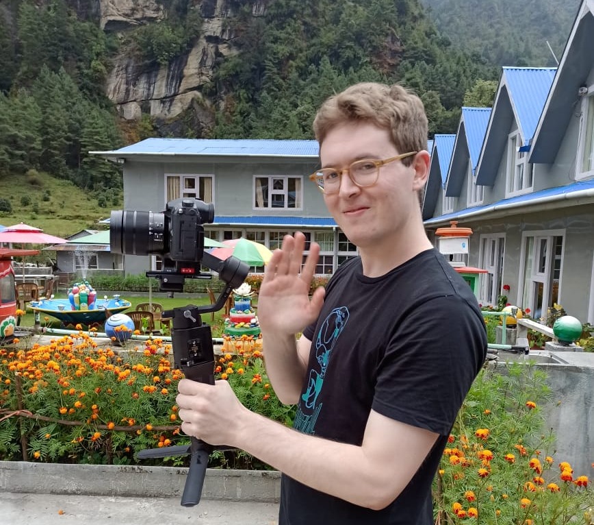 Brendan holding video camera and waving at camera on EBC trek, Nepal