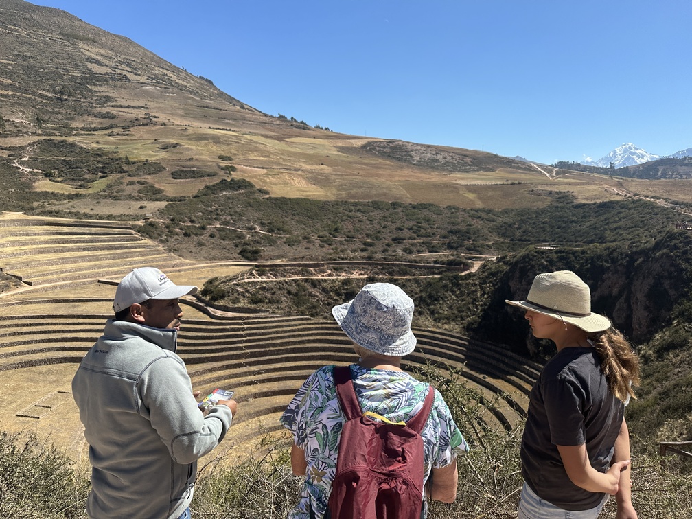 Ariana. View of three people looking down to Moray ruins, Sacred Valley in winter, Peru