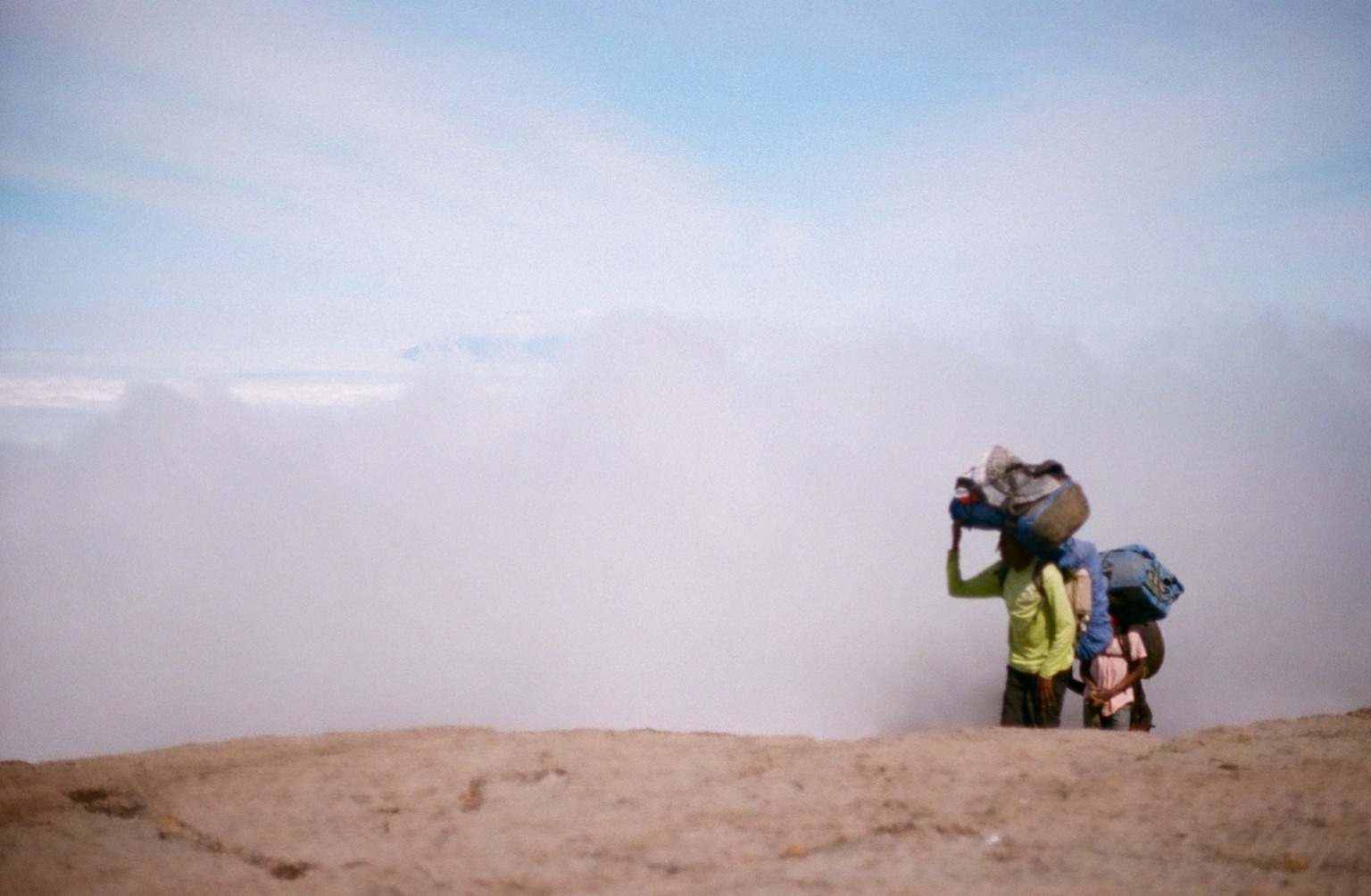 Jillian Tofukji. Porters on Kilimanjaro with clouds behind