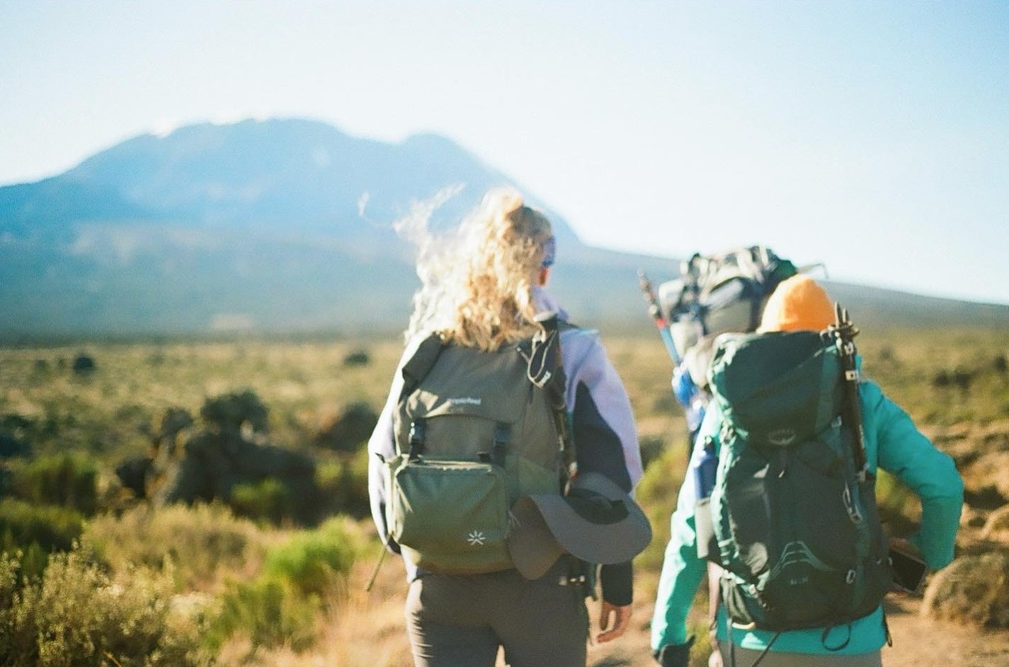 Jillian Tofukuji. Female hikers walking towards Kilimanjaro