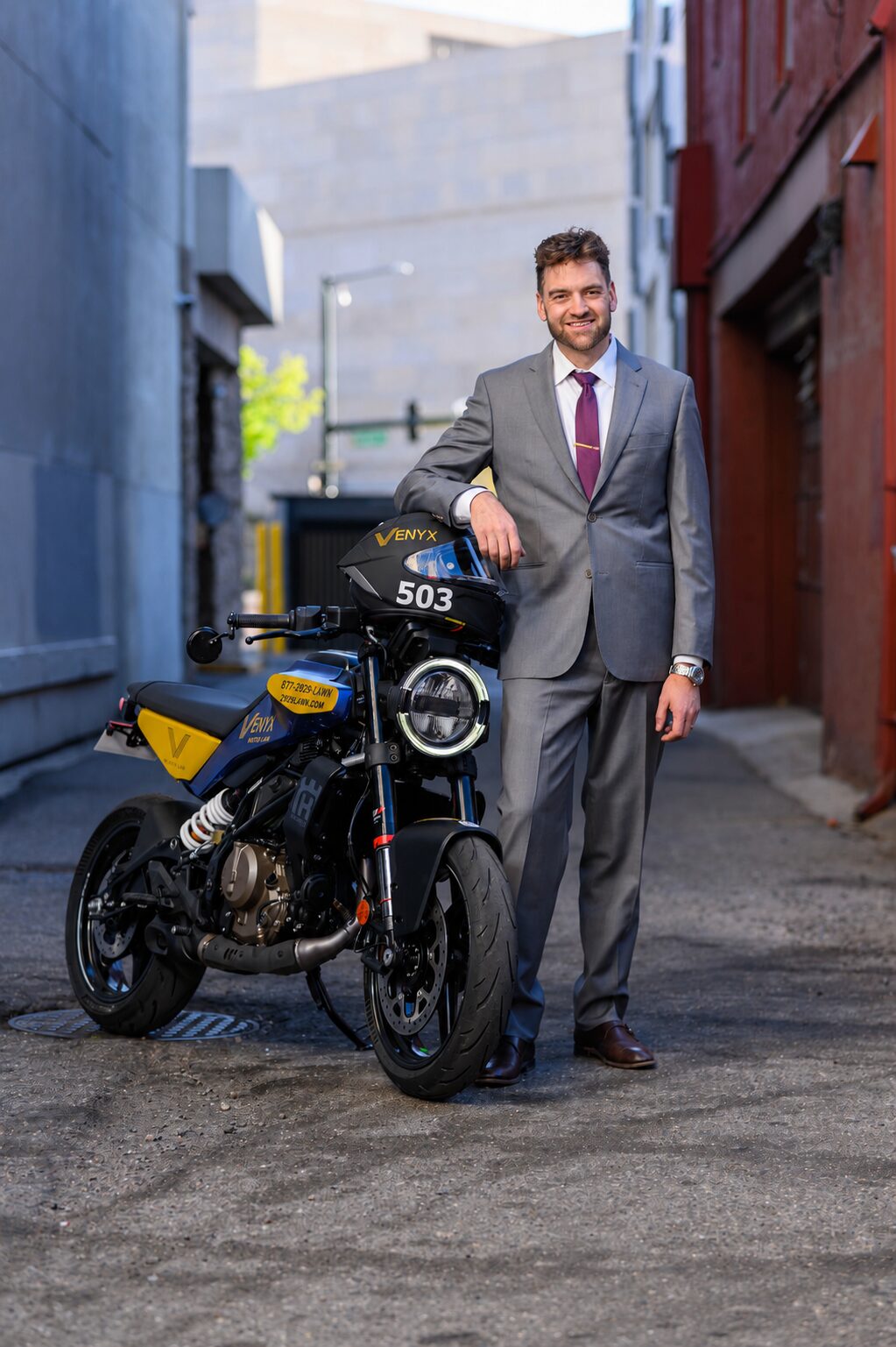 Dylan Unger, Denver motorcycle accident attorney, beside his VENYX-branded race bike