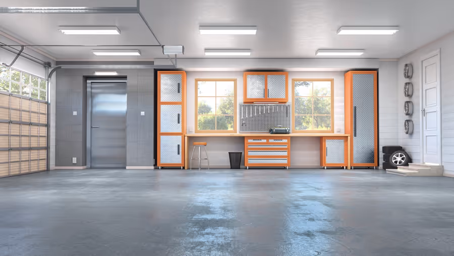 Clean, empty garage interior with polished concrete floor, orange and silver storage cabinets, two windows, and a closed metal door.