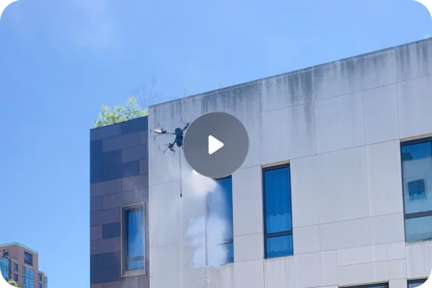Modern high-rise building viewed from below with abstract geometric mural and blue sky with clouds.
