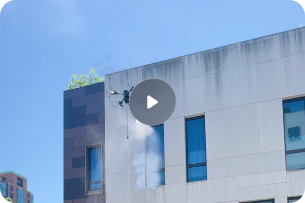 Modern high-rise building viewed from below with abstract geometric mural and blue sky with clouds.