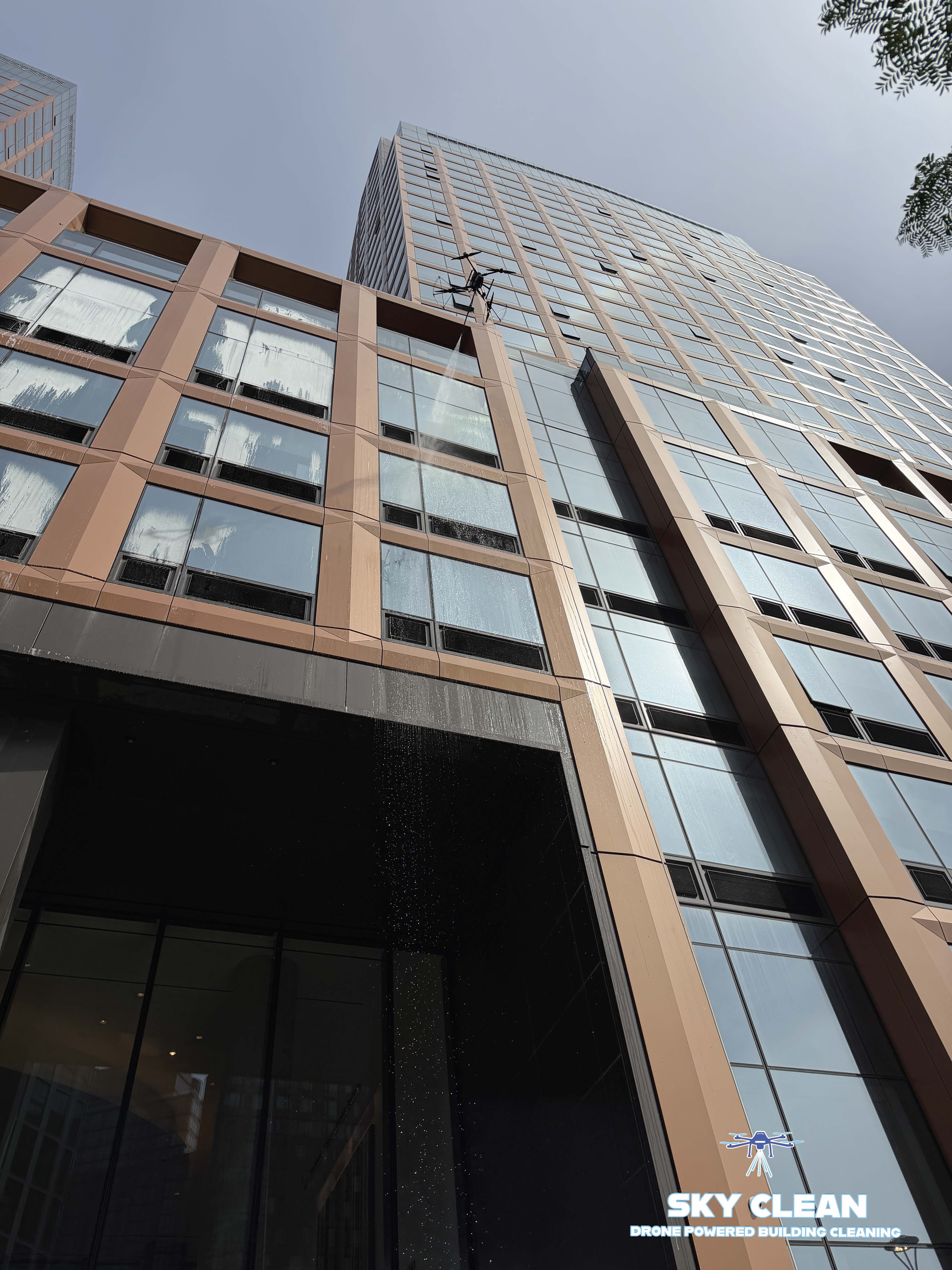 Modern high-rise building viewed from below with abstract geometric mural and blue sky with clouds.
