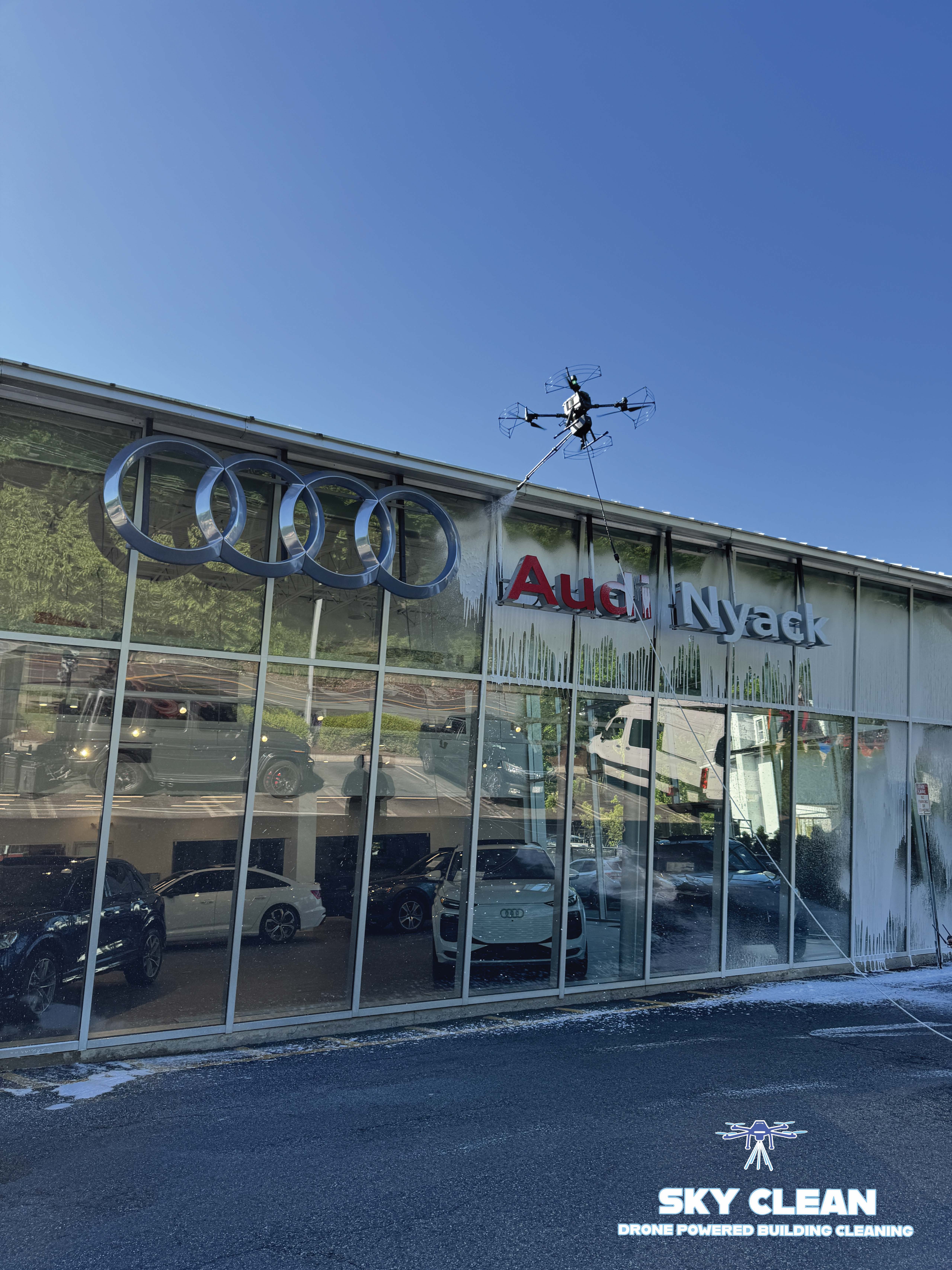 Modern high-rise building viewed from below with abstract geometric mural and blue sky with clouds.