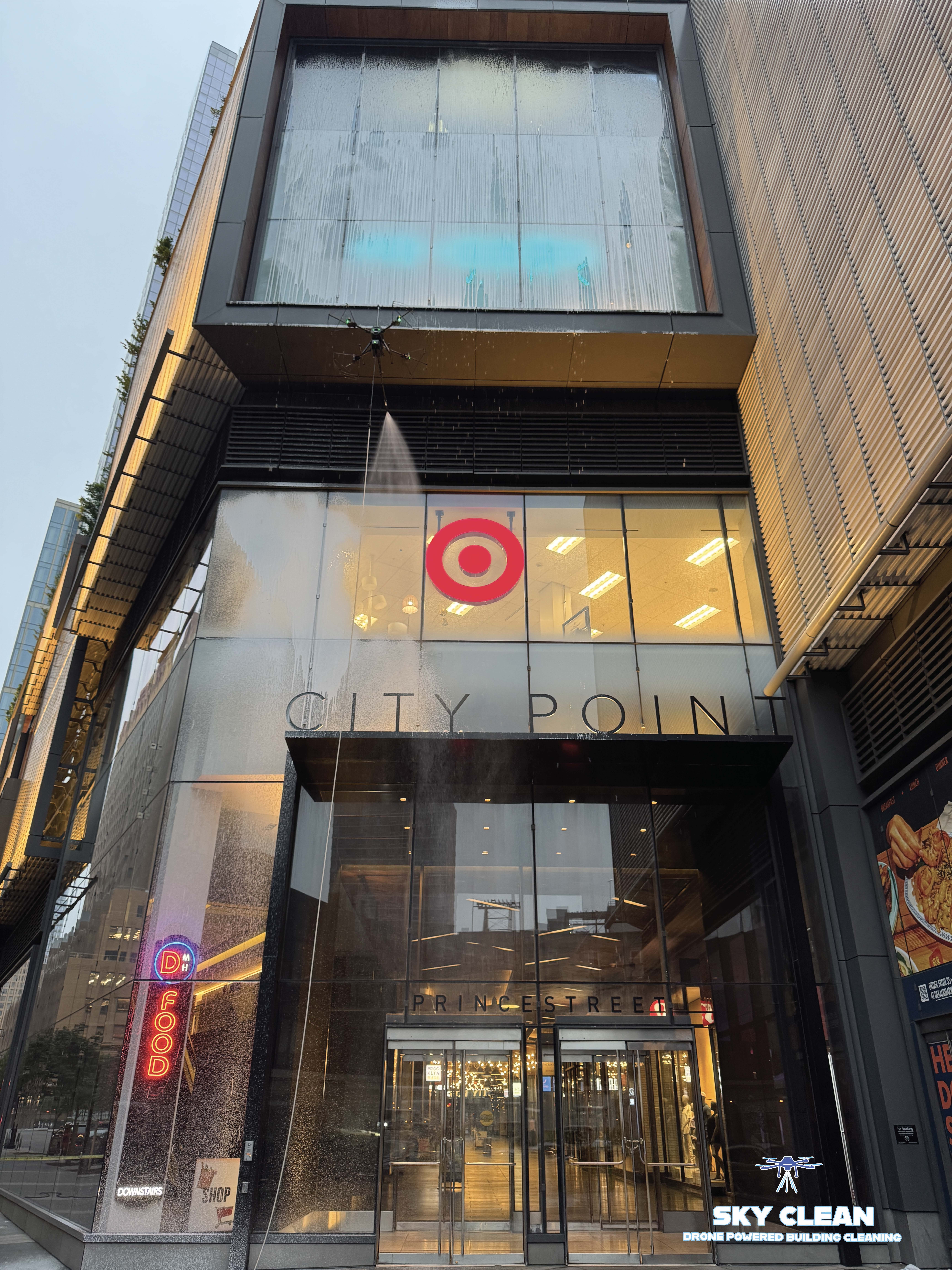 Modern high-rise building viewed from below with abstract geometric mural and blue sky with clouds.