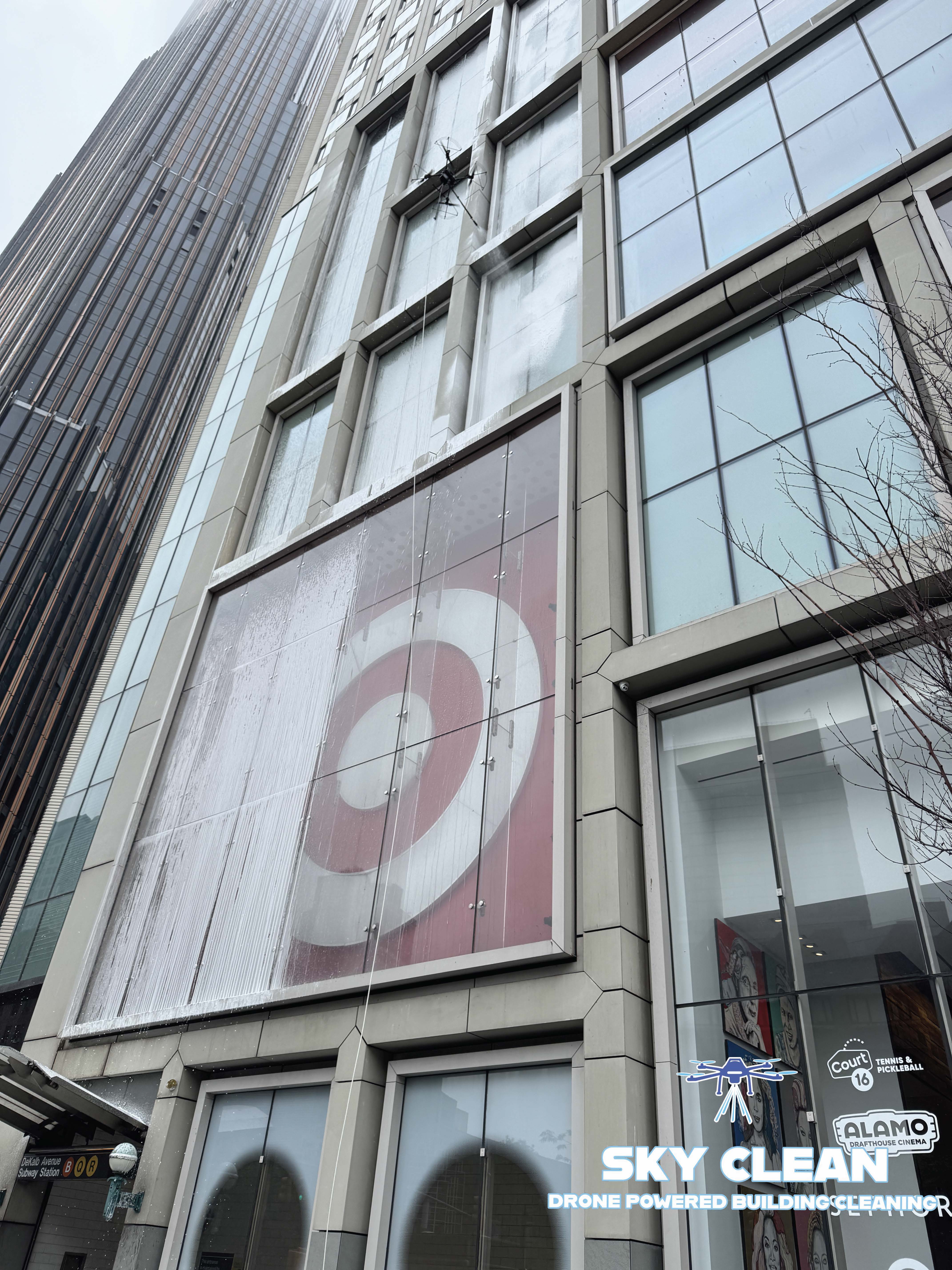 Modern high-rise building viewed from below with abstract geometric mural and blue sky with clouds.