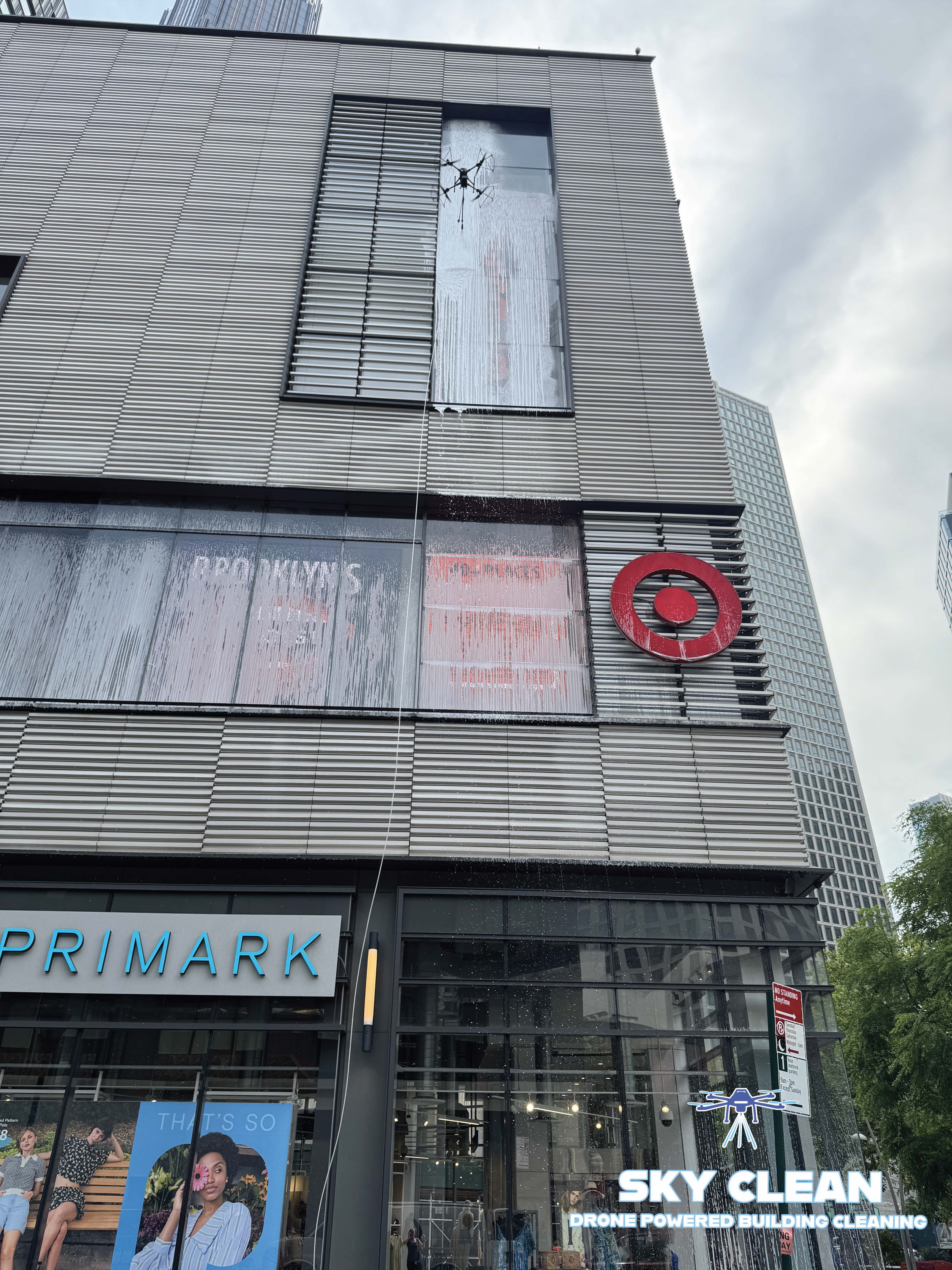 Modern high-rise building viewed from below with abstract geometric mural and blue sky with clouds.