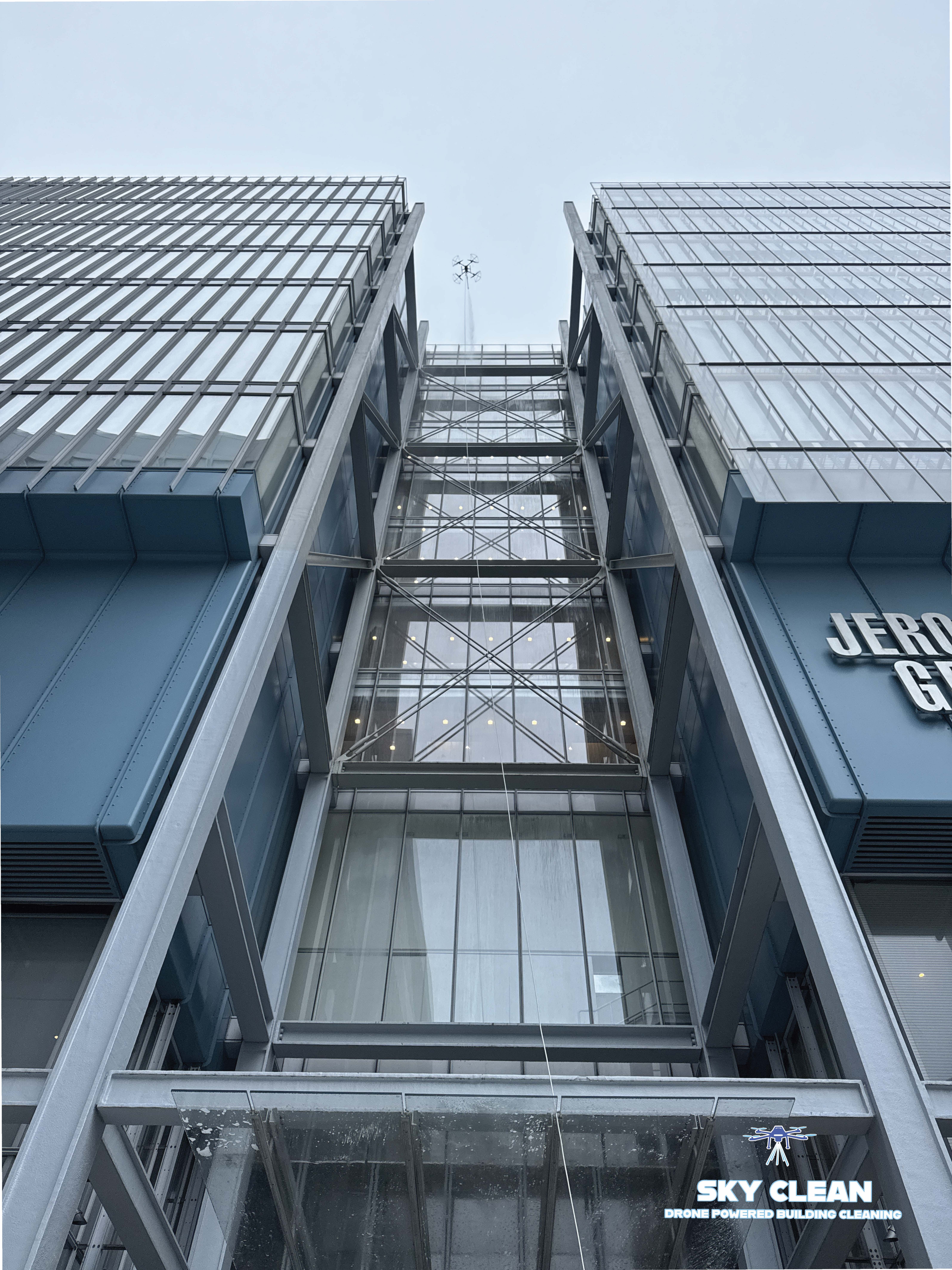 Modern high-rise building viewed from below with abstract geometric mural and blue sky with clouds.