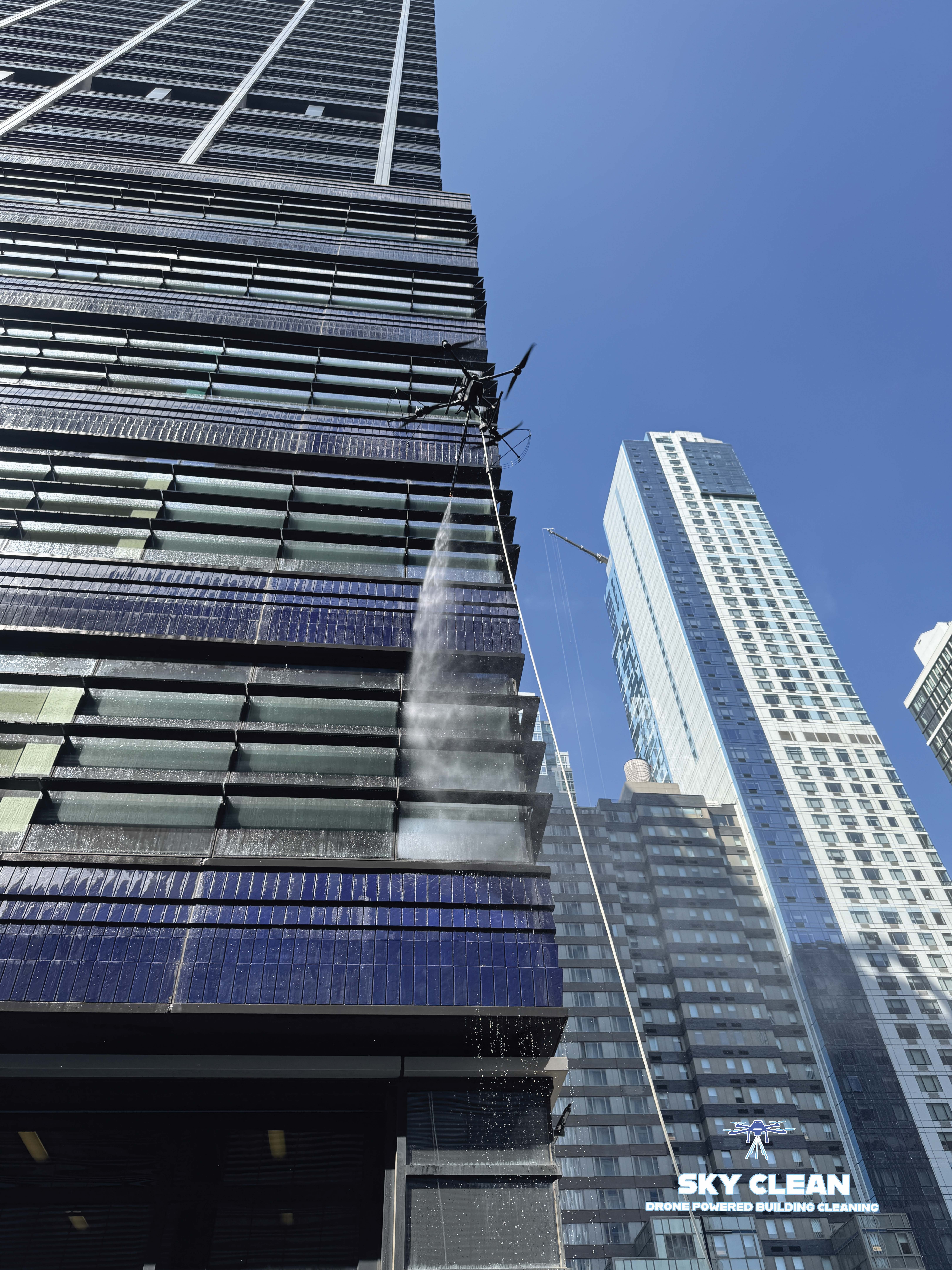 Modern high-rise building viewed from below with abstract geometric mural and blue sky with clouds.