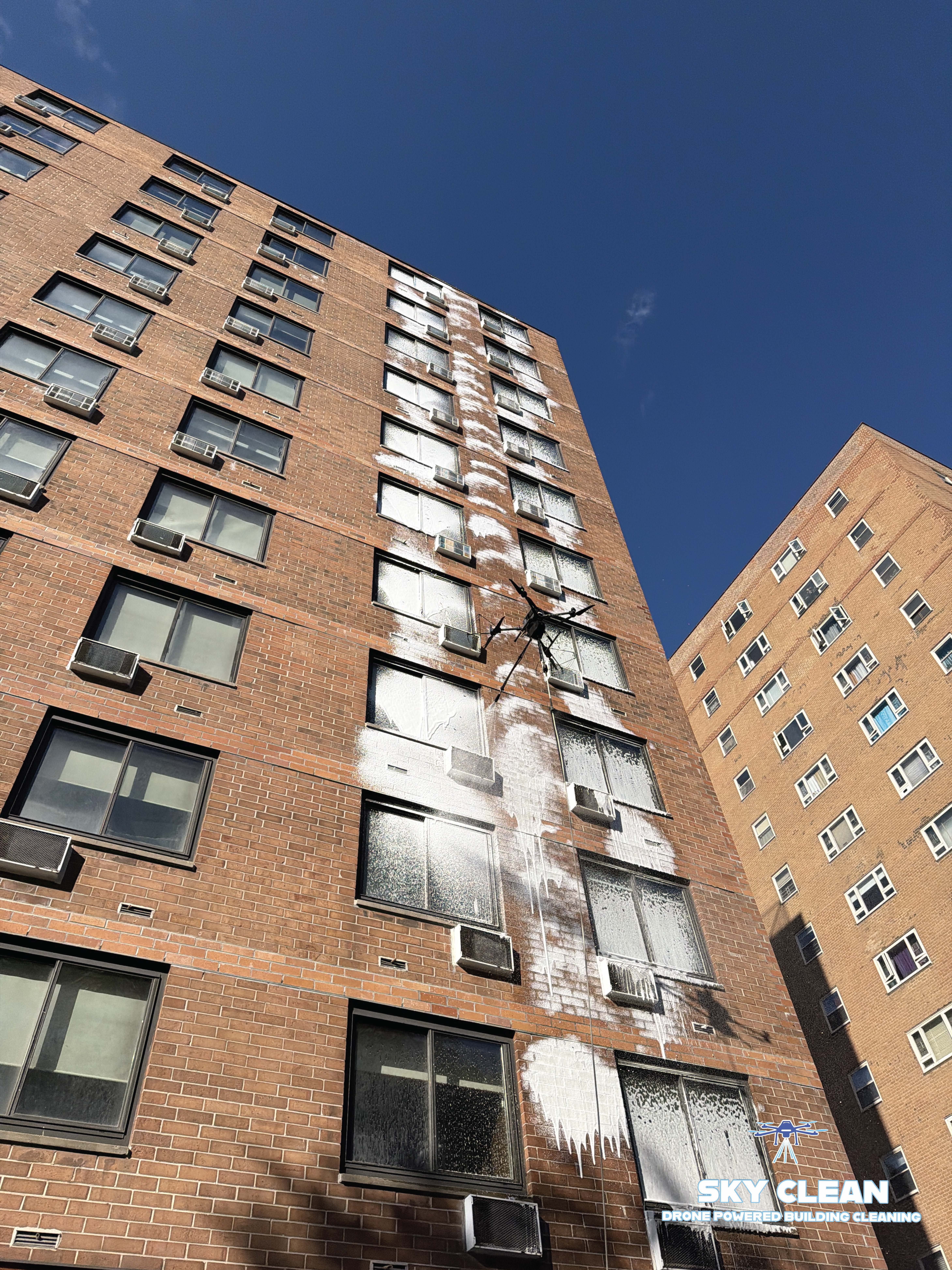 Modern high-rise building viewed from below with abstract geometric mural and blue sky with clouds.