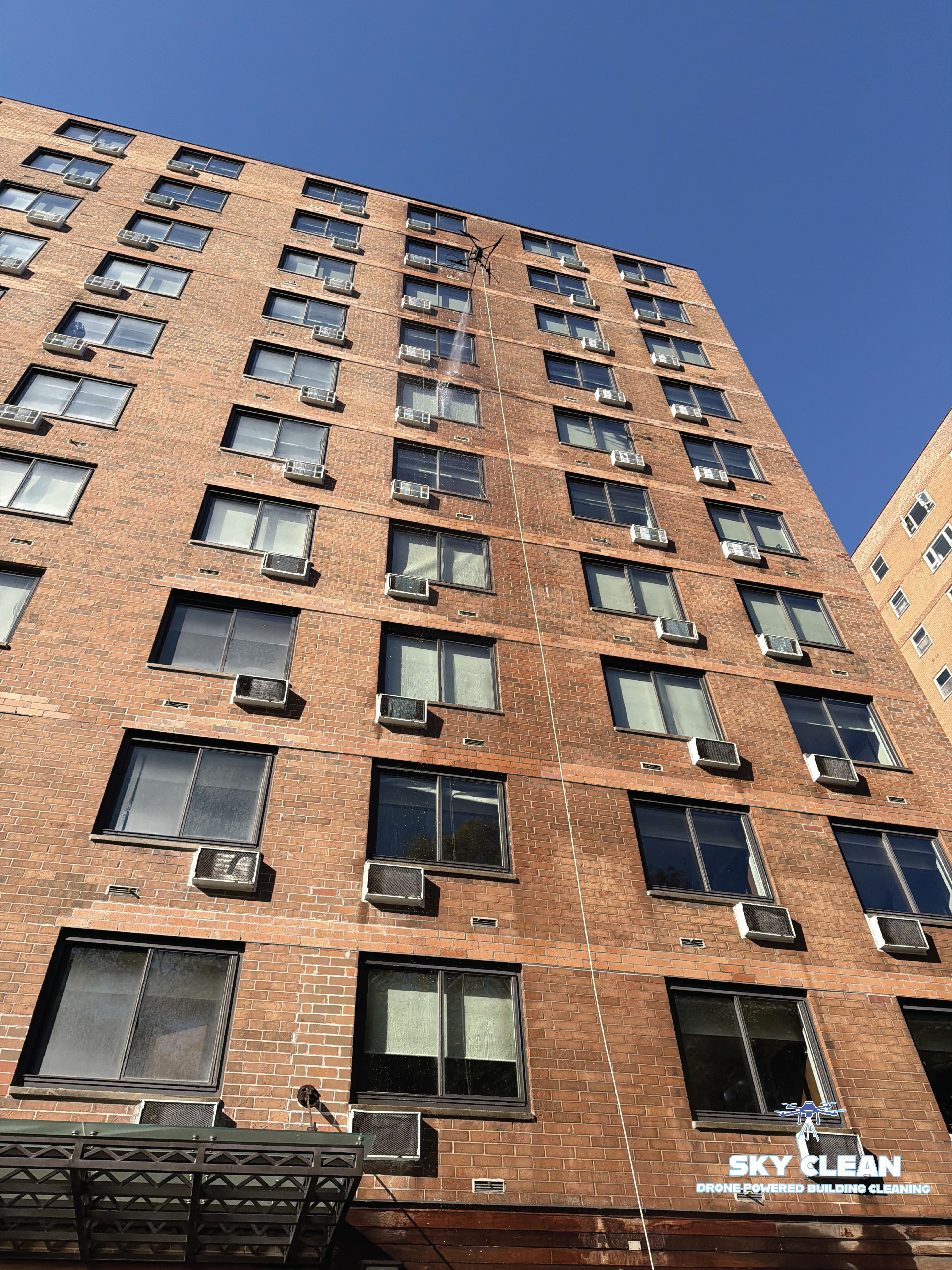 Modern high-rise building viewed from below with abstract geometric mural and blue sky with clouds.