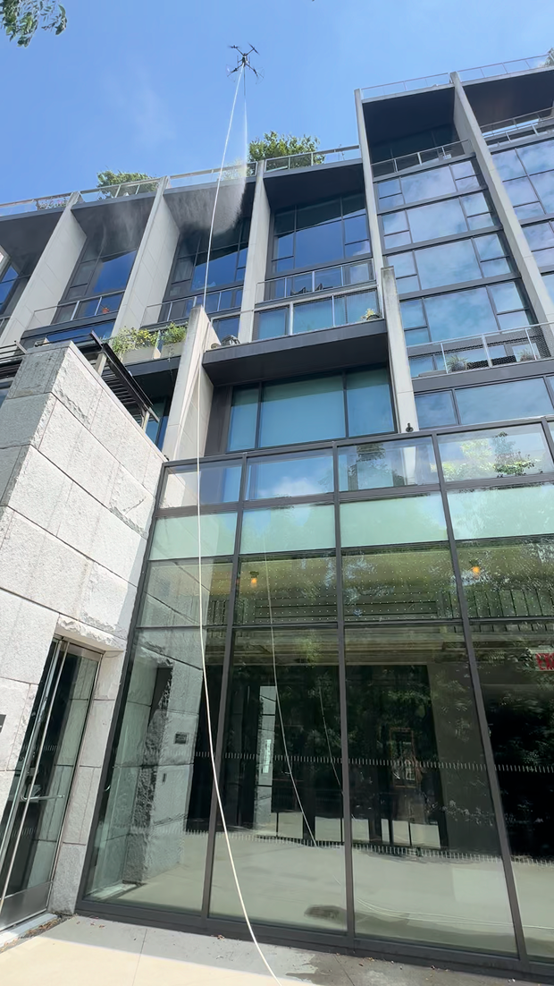 Modern high-rise building viewed from below with abstract geometric mural and blue sky with clouds.