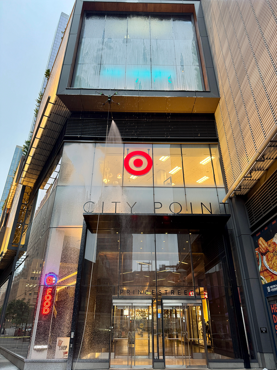 Modern high-rise building viewed from below with abstract geometric mural and blue sky with clouds.