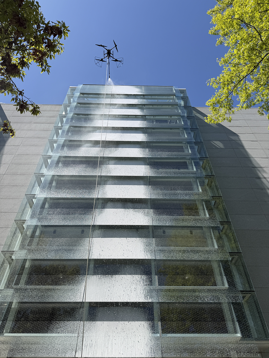 Modern high-rise building viewed from below with abstract geometric mural and blue sky with clouds.