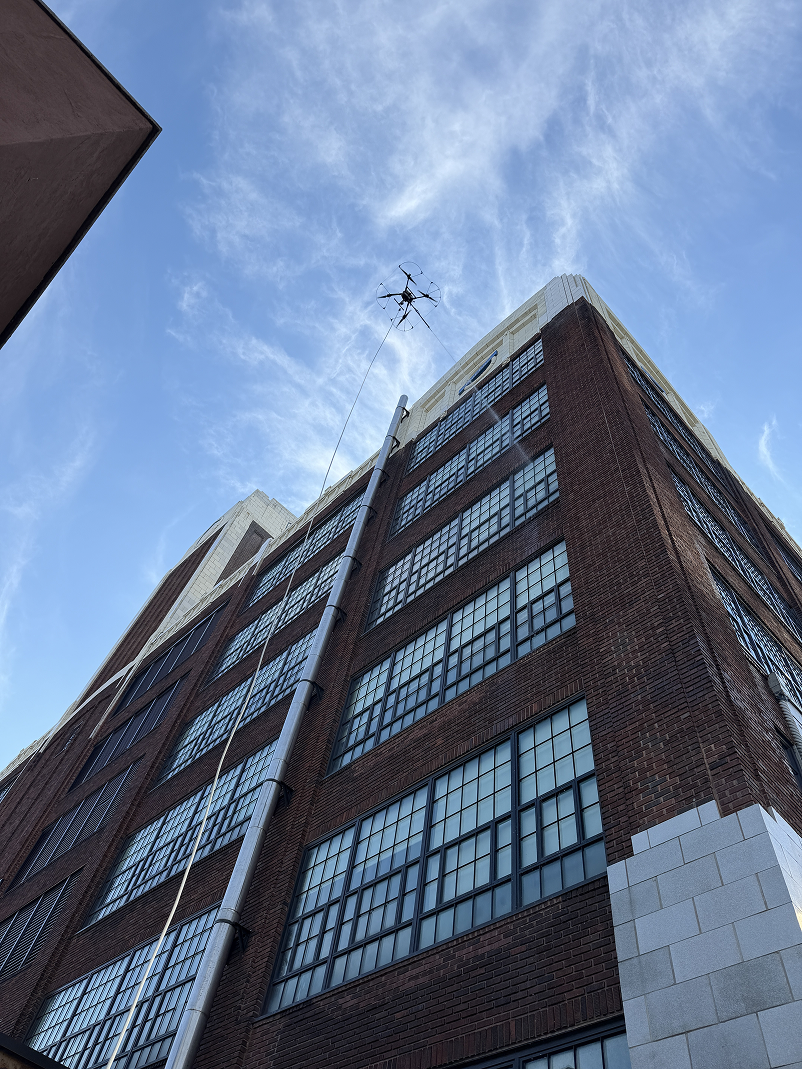 Modern high-rise building viewed from below with abstract geometric mural and blue sky with clouds.